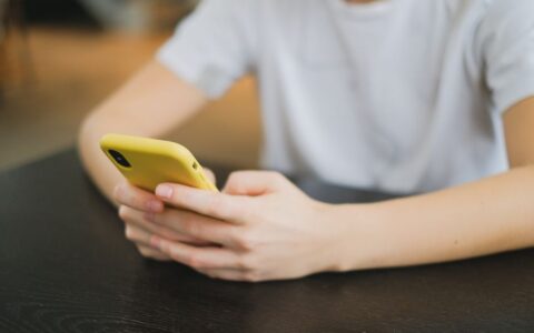 Close-up of person holding a yellow smartphone indoors, focused on the hands and gadget.