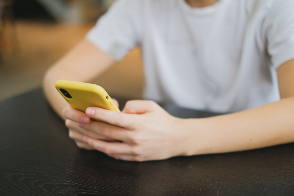 Close-up of person holding a yellow smartphone indoors, focused on the hands and gadget.