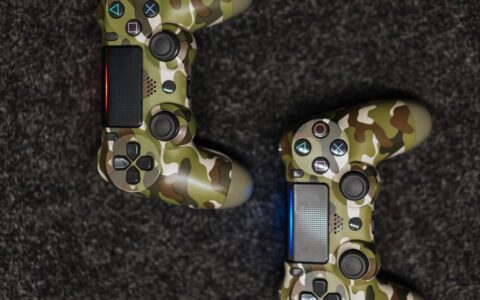 Close-up view of camouflage-patterned game controllers on a dark carpet background.