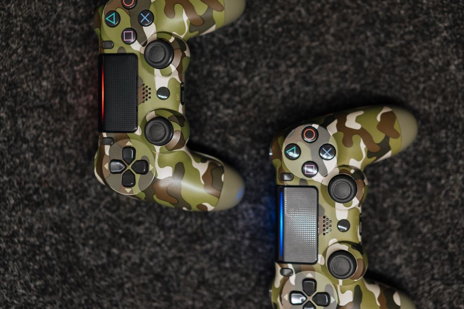 Close-up view of camouflage-patterned game controllers on a dark carpet background.