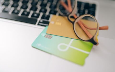 Close-up of eyeglasses and credit cards on a laptop, emphasizing finance and technology.
